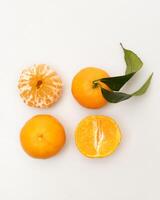 oranges and tangerines with leaves whole and in size lie on a white background photo