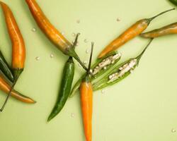 yellow red orange chili peppers lie on a green background photo