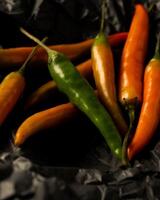 yellow and green chili peppers lie on black craft paper photo