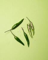 yellow red orange chili peppers lie on a green background photo