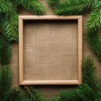 Christmas frame made of fir branches on a burlap background. Linen background. Eco-friendly homemade New Year's decor with copy space. photo