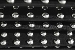 leather and metal abstract background with patches of black bullskin and shiny metal rivets in the style of bikers and rocknroll lovers of the 80s and 90s. High quality photo