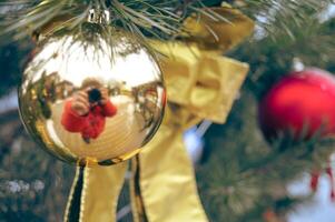 a golden toy on the Christmas tree in which a photographer with a camera is reflected. High quality photo