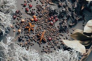 various spices scattered on a dark background with bunches of grass, laurel leaves, berries and other spices for cooking fragrant Eastern and Midwestern food. High quality photo