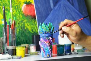decorating a ceramic mug vessel with the hands of a master at a work table. photo without a face. the workspace of the master of pottery and ceramics is modern art and handmade art workshop. High