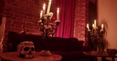 Burning candles with spooky skull on table at home video