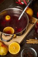 Warm mulled wine with spices and citrus slices served in a pot photo