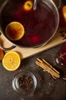 Mulled wine preparation with oranges, spices, and cinnamon sticks on a wooden table photo