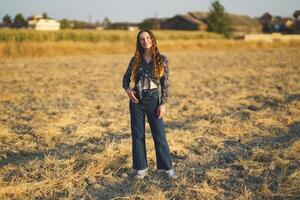A Young Woman is Gracefully Posing in a Sunlit Field While Wearing a Charming Vintage Style Outfit photo