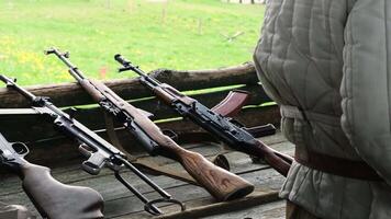 A soldier picks up a machine gun from a table in slow motion video
