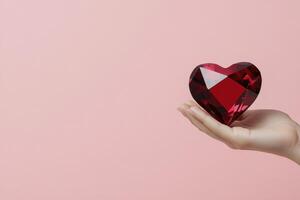 Heart shaped gemstone held in a hand against a soft pink background photo