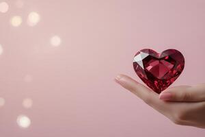 Heart shaped gemstone held in a hand against a soft pink background photo