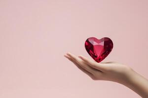 Heart shaped gemstone held in a hand against a soft pink background photo