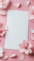 Decorative paper flowers and hearts surrounding a blank white sheet on a light background photo