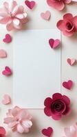 Decorative paper flowers and hearts surrounding a blank white sheet on a light background photo
