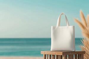 White tote bag resting on a wooden table near the beach with calm water and clear sky photo