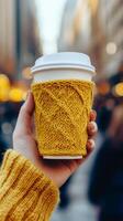 Cozy warm drink held in a hand in a bustling city street during late afternoon photo