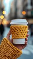 Cozy warm drink held in a hand in a bustling city street during late afternoon photo