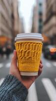 Cozy warm drink held in a hand in a bustling city street during late afternoon photo