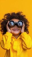 Child with binoculars enjoys playful exploration against a vibrant yellow background photo