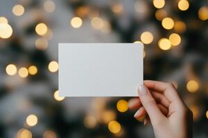 Hand holding blank card in front of sparkling lights during festive season photo