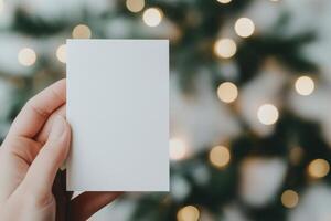 Hand holding blank card in front of sparkling lights during festive season photo