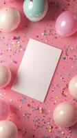 Colorful party setup with balloons and confetti around a blank card on a pink background photo
