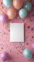 Colorful party setup with balloons and confetti around a blank card on a pink background photo