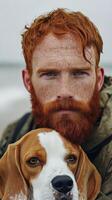 Red haired man with freckles and his beagle dog in a natural outdoor setting photo