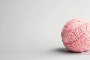 Soft pink yarn ball resting on a clean white surface in a cozy craft space photo
