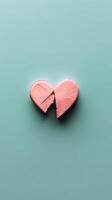 Broken heart shaped object in pastel pink color on light blue surface photo