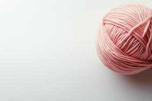 Soft pink yarn ball resting on a clean white surface in a cozy craft space photo