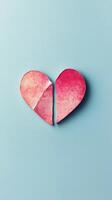 Broken heart shaped object in pastel pink color on light blue surface photo