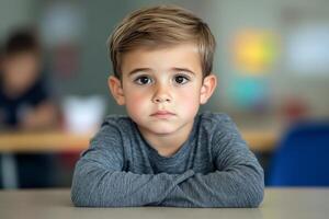 Young child sitting alone at a desk in a classroom during daytime learning photo