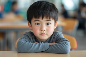 Young child sitting alone at a desk in a classroom during daytime learning photo
