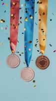Medals hang against a blue background with confetti celebrating achievement photo