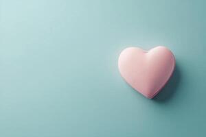 Pink heart shaped piece broken on a light blue background representing love and relationships photo