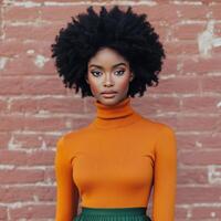 Young woman poses in vibrant orange sweater with green backdrop in modern studio photo