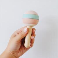 Colorful wooden toy shaker held by a hand against a light background photo