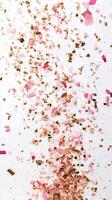 Colorful confetti made of pink petals and gold flakes falling gracefully from above photo