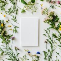 Blank cards surrounded by fresh flowers and greenery on a light textured surface photo