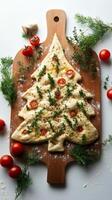 Festive dough shaped like a Christmas tree with tomatoes and herbs for holiday baking photo