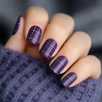 Stylish purple plaid nail design with golden accents on cozy sweater background photo