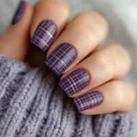 Stylish purple plaid nail design with golden accents on cozy sweater background photo