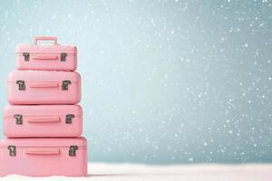 Colorful pink suitcases stacked on snow during a gentle snowfall in a winter landscape photo