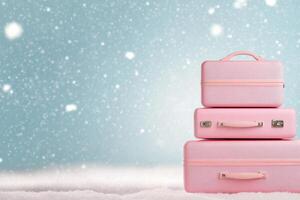 Colorful pink suitcases stacked on snow during a gentle snowfall in a winter landscape photo