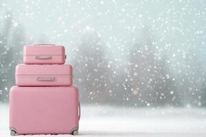 Colorful pink suitcases stacked on snow during a gentle snowfall in a winter landscape photo