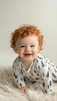 Happy baby with curly red hair smiling while playing indoors on soft blanket photo