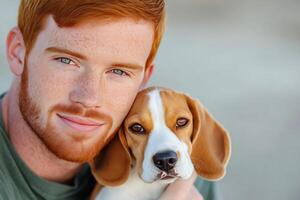 Young man with red hair cuddles beagle puppy at outdoor location during sunny weather photo