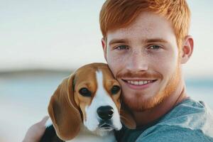 Young man with red hair cuddles beagle puppy at outdoor location during sunny weather photo